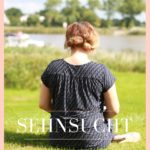 Eine Frau sitzt mit dem Rücken zur Kamera und schaut auf die Elbe. Sie trägt einen blauen Anzug und schaut in die Ferne mit der Aufschrift "das Gefühl nicht komplett zu sein - Sehnsucht - www.ferierSun.de!