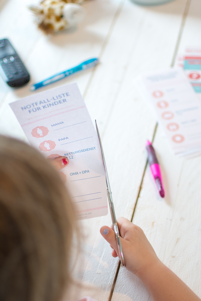 Kind bastelt sich eine Notall-Liste mit den wichtigsten Telefonnummern und scheidet die Liste aus. Diese Liste gibt es als Design-Freebie auf dem Blog feierSun.de