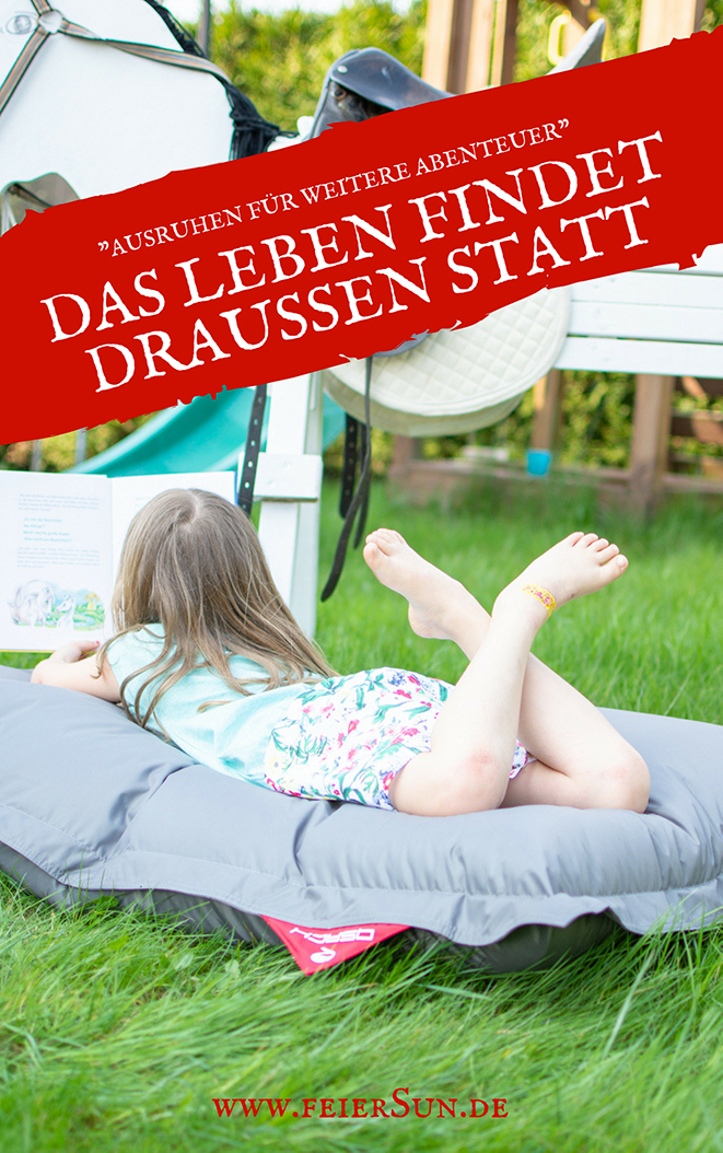 Mädchen liegt auf einem grauen Sitzsack von QSacks und liest ein Buch über Pferde und Fohlen. Auf dem Bild steht folgende Schrift "Ausruhen für weiter Abenteuer. Das Leben findet draußen statt - www.feiersun.de"
