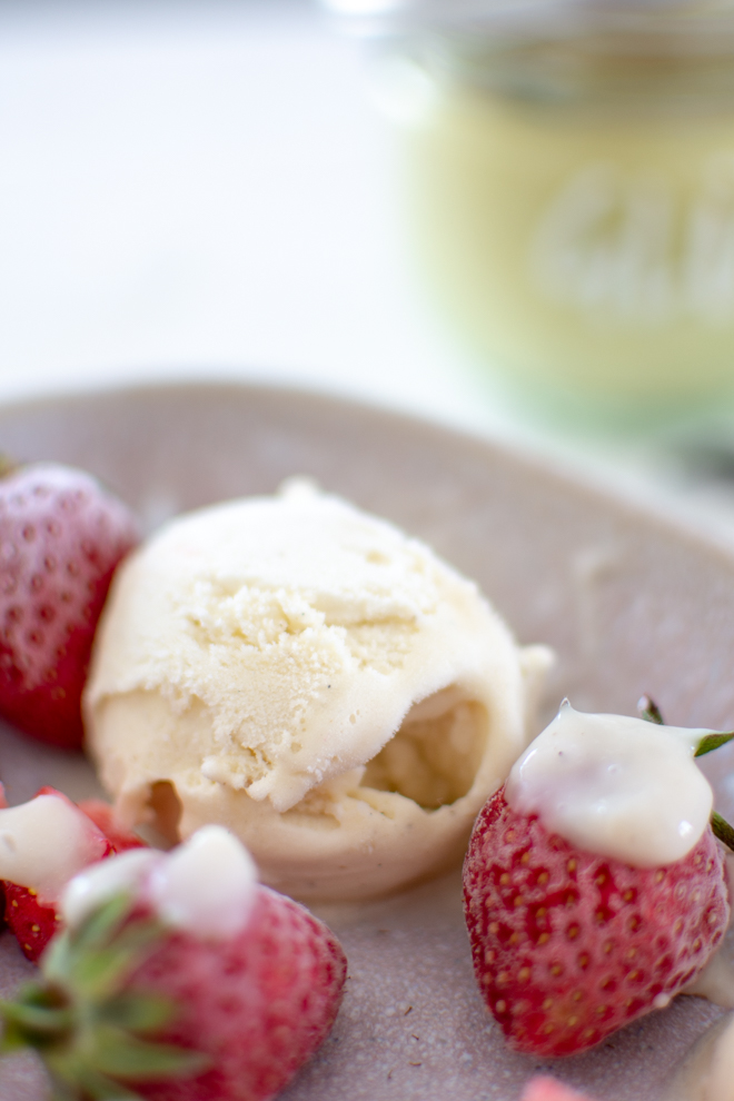 Vegane Vanillesoße mit einer Kugel Eis und Erdbeeren auf einem Teller angerichtet und der Beschriftung "Vanillesosse einfach und schnell selber machen"von www.feiersun.de