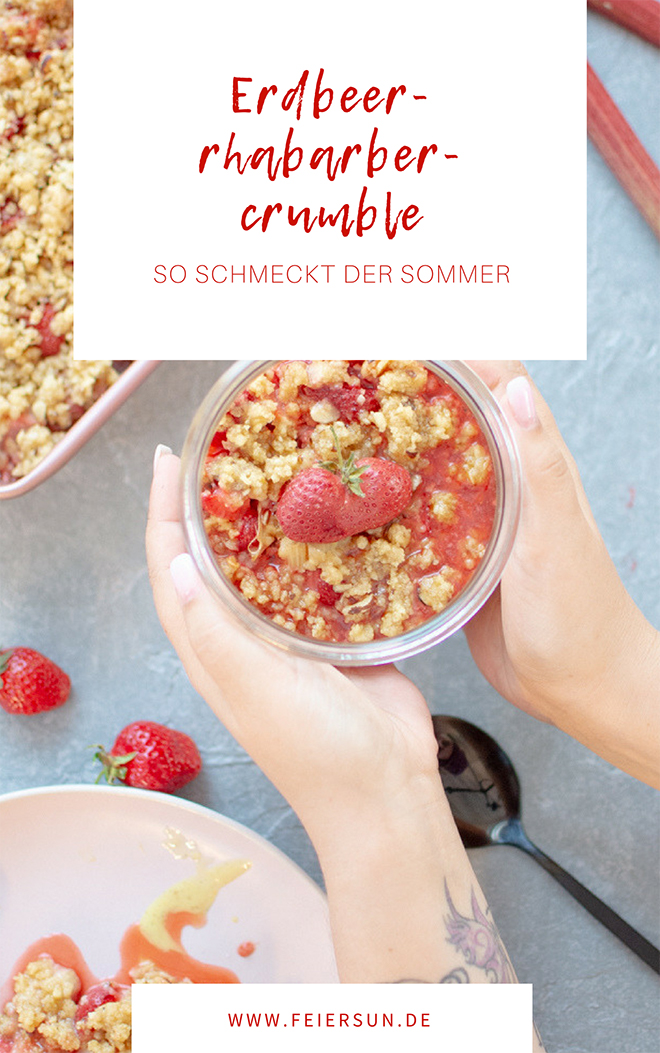 Erdbeer-Rhabarber-Crumble fertig fotografiert im Glas mit händen umklammert.